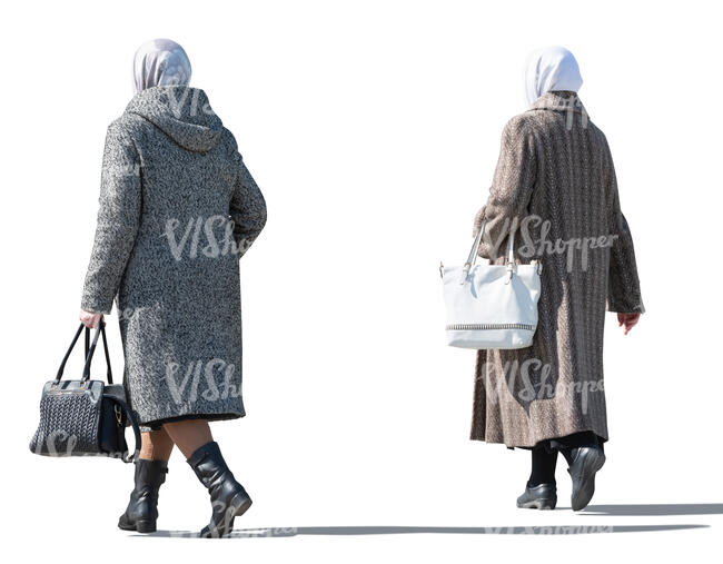 two sidelit older women in overcoats walking