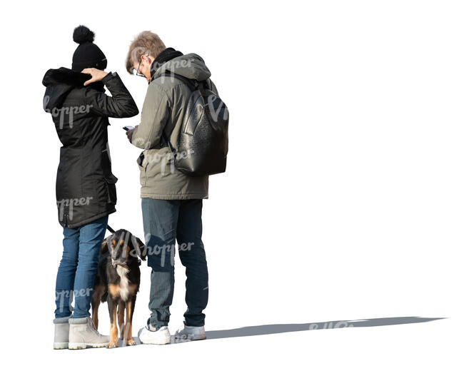 two cut out people with a dog standing in winter