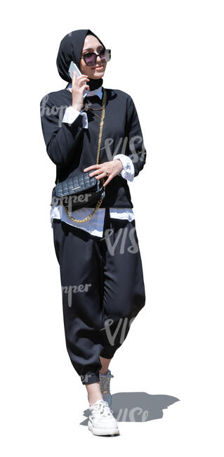 cut out young muslim woman walking and talking on a phone