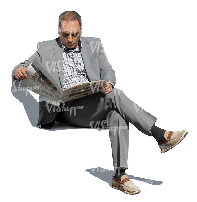 older man in a grey suit sitting and reading a newspaper