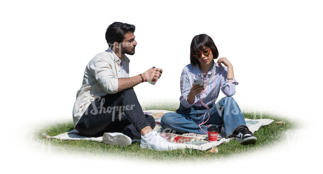 two people sitting in the park on the grass and drinking coffee