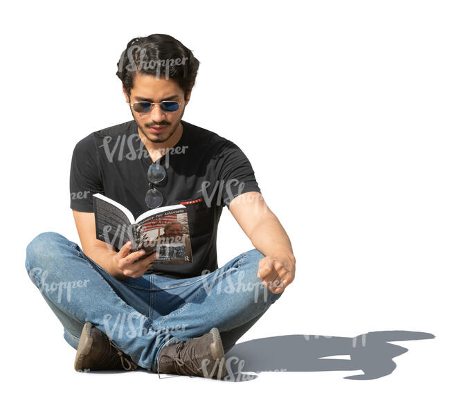 man sitting on the ground outside and reading a book