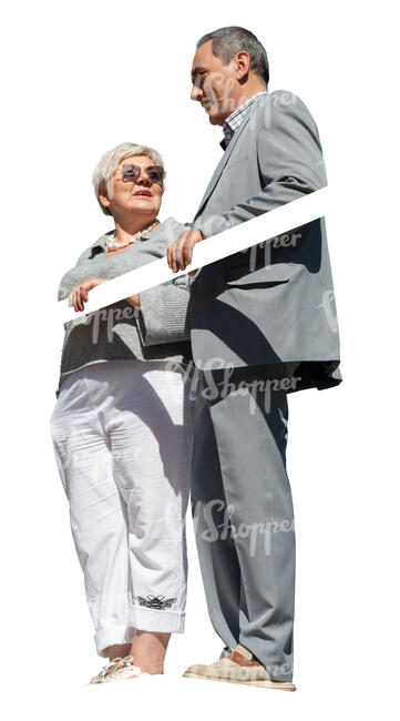 two older people standing up on a balcony and talking