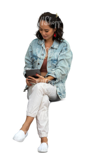 asian woman sitting and reading smth from a tablet
