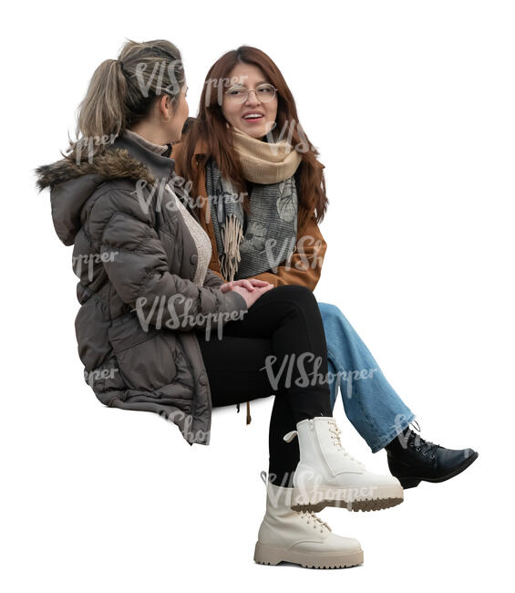 two women wearing overcoats sitting and talking