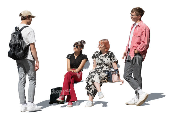 two boys standing and talking to two girls sitting