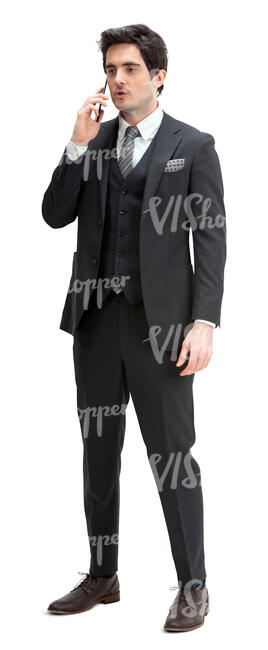 man in a black suit standing and talking on a phone