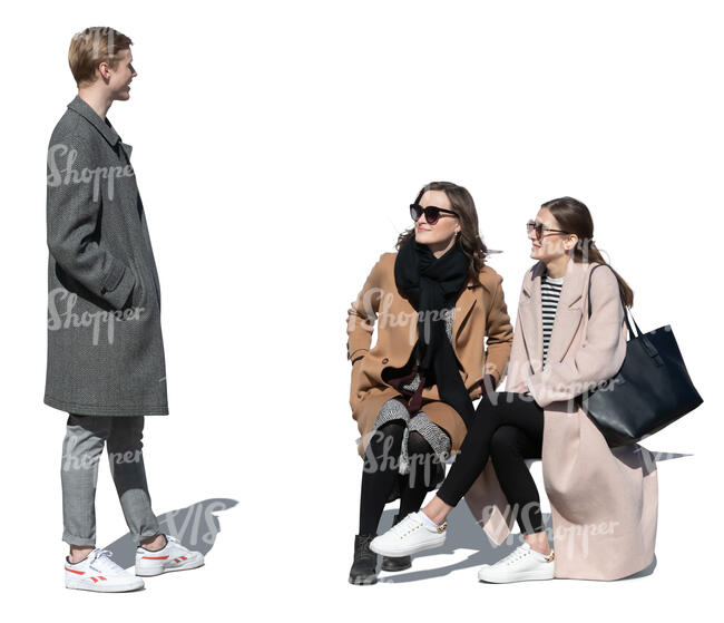 two women sitting and talking to a young man