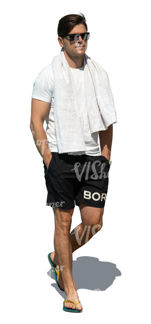 man in shorts and flipflops and carrying a towel walking