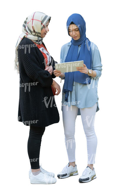 two muslim girls standing and looking at an ipad