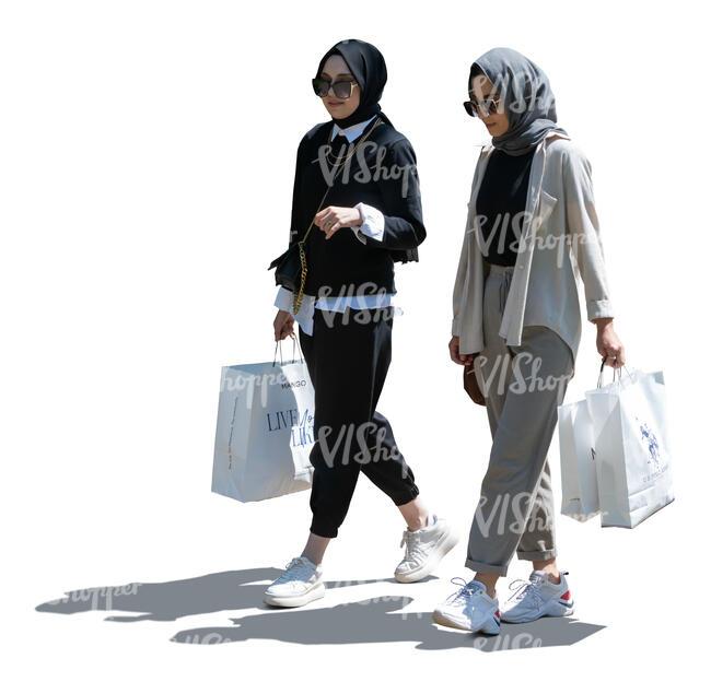 two backlit middle eastern women with shopping bags walking