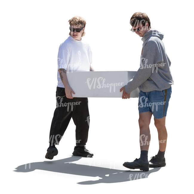 two backlit young men carrying a large box