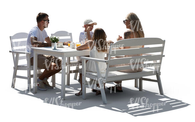 backlit family sitting in a garden by a table and eating  