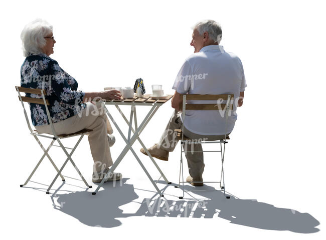 backlit senior couple sitting in a street cafe