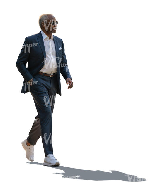 backlit black man in a grey suit walking