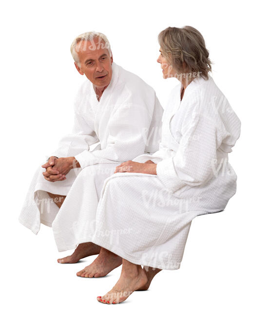 older man and woman in white bathrobes sitting and talking