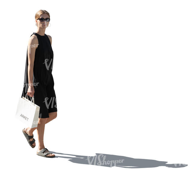 backlit woman in a black dress carrying a shopping bag walking