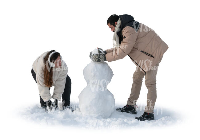 man and woman building a snowman in winter