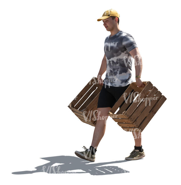 backlit man carrying wooden crates