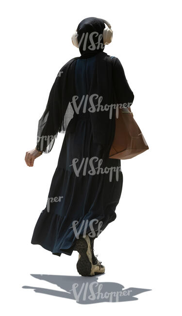 backlit muslim woman with headphones walking