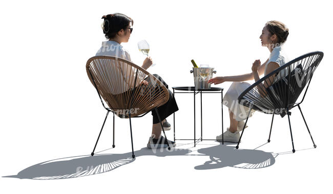 two backlit asian women sitting and drinking wine