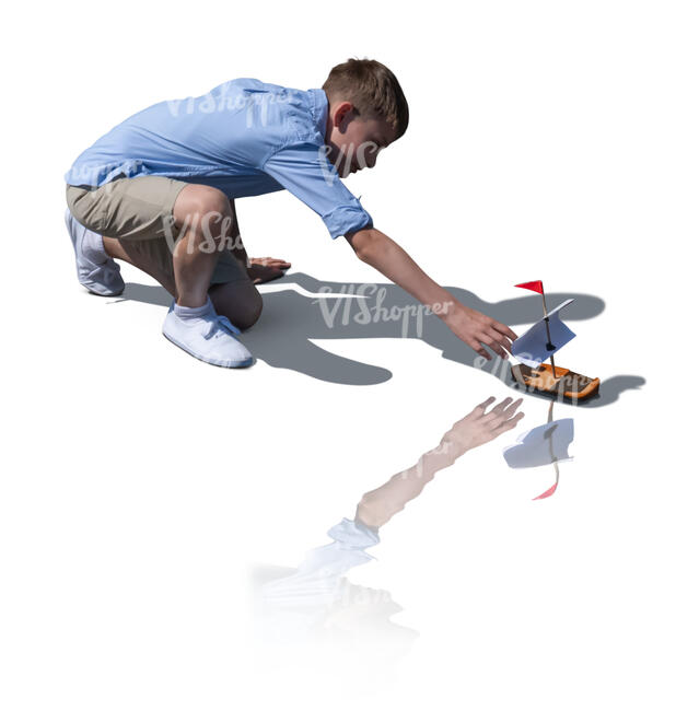 cut out boy playing with a toy boat by the water