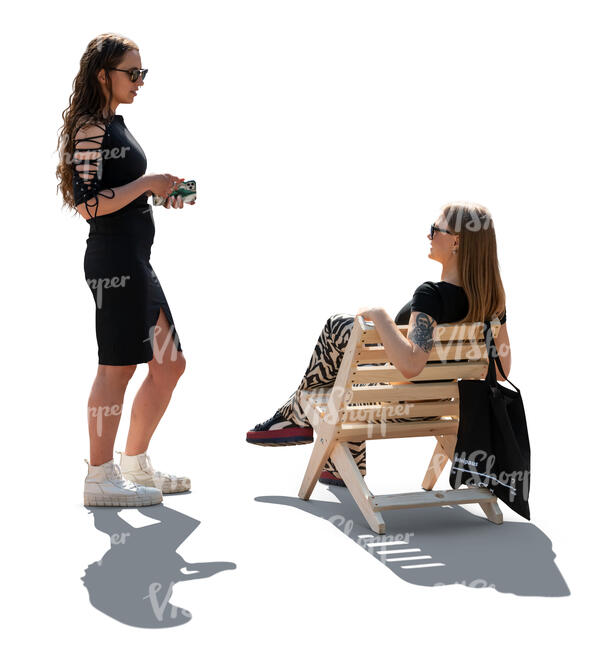 backlit woman standing and talking to her friend sitting on the chair