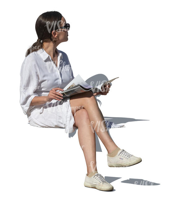 woman in a summer dress sitting and reading a magazine