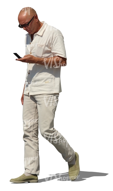 man in white walking with a phone in his hand