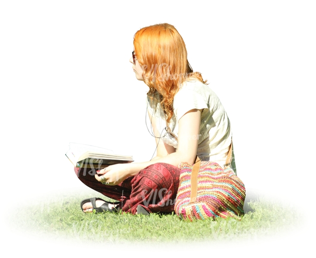 red-haired woman sitting on the grass and reading a book