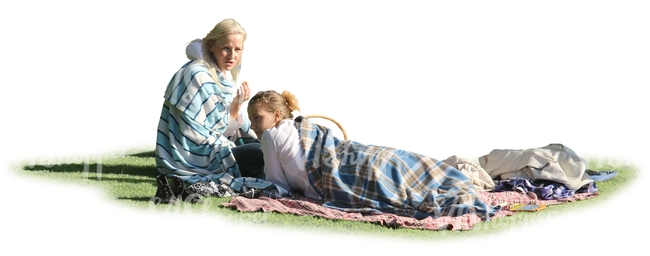 two women wrapped in blankets sitting on the grass