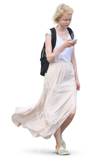 woman in white outfit walking and looking at her smartphone