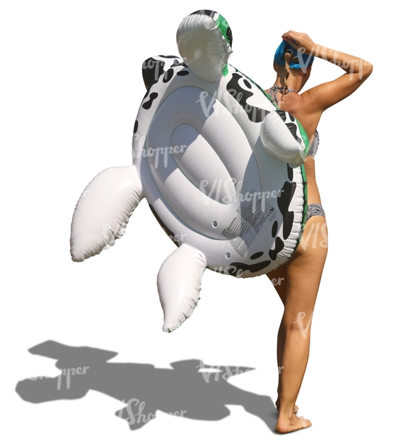 woman in a bikini with an inflatable toy walking on the beach