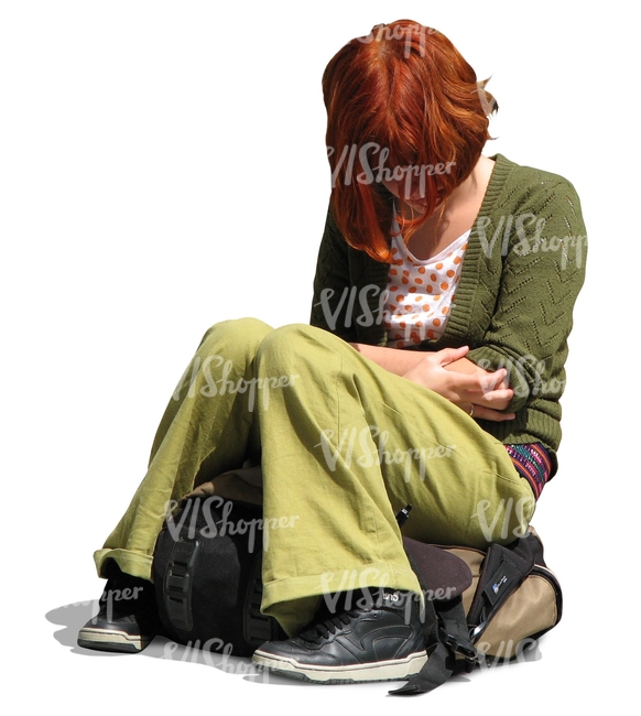 young woman with red hair and green clothes sitting on her backpack