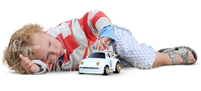 little boy lying and playing with a toy car