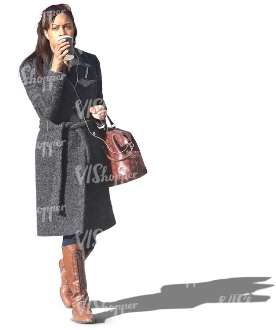 black woman in a grey coat walking and drinking coffee