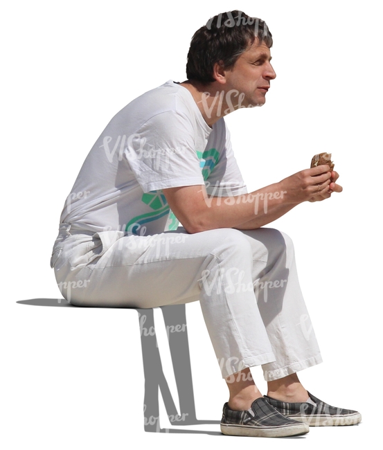 man in white clothes sitting and eating
