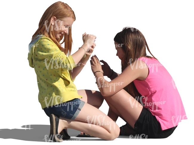 two girls sitting on the ground and playing