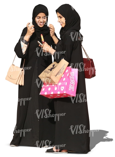 two young arab women in abayas standing and smiling