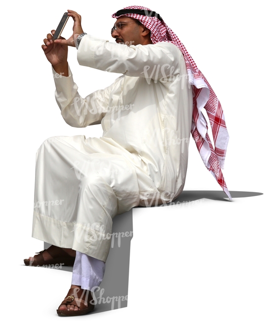 arab man in a thobe sitting and taking a picture