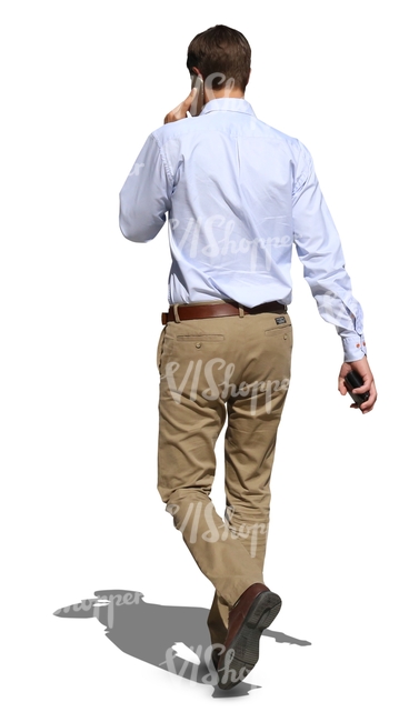 man in a white shirt walking and talking on the phone