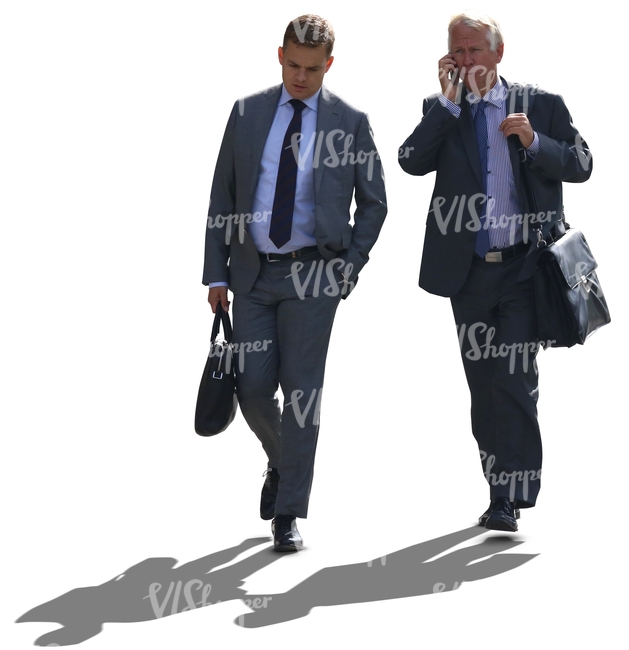 two backlit businessmen walking side by side