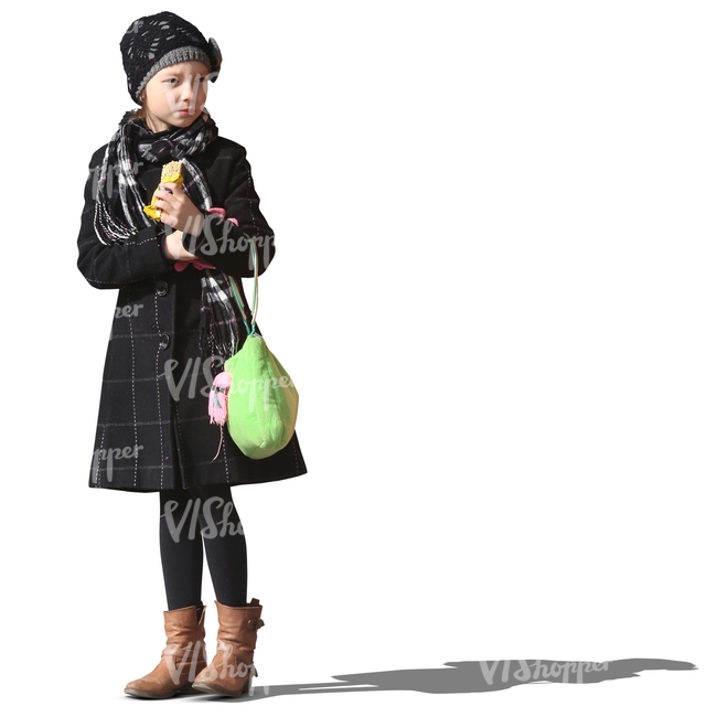 young girl in a winter coat standing and eating a snack