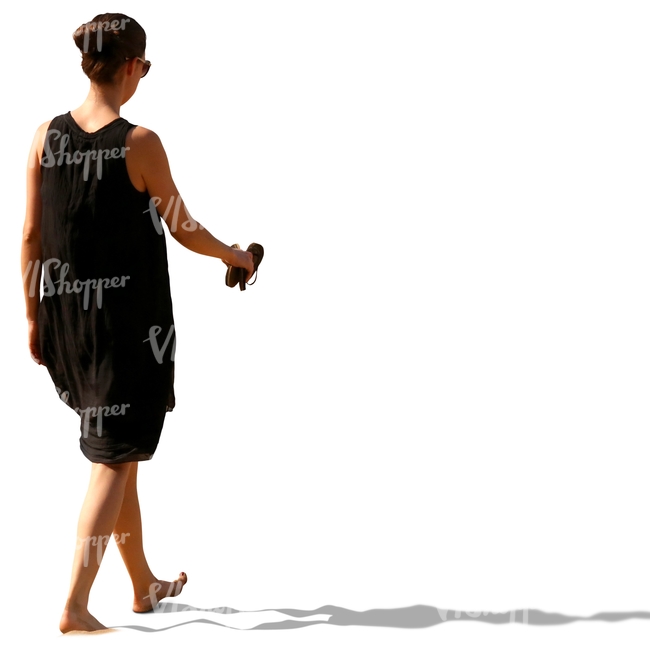 woman in a black summer dress walking barefoot on the beach