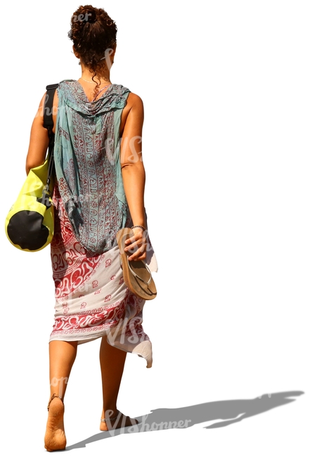 woman walking barefoot and carrying a yoga mat bag and sandals