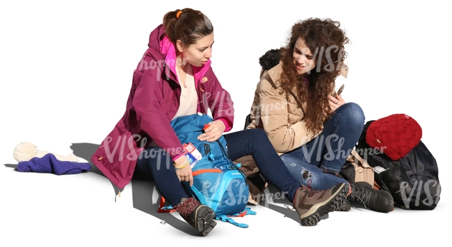 two women sitting on the sidewalk and talking