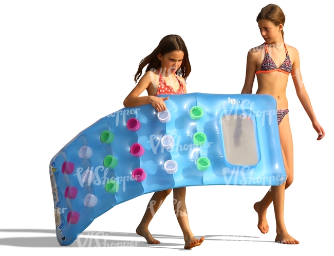 two girls carrying a floatie on the beach