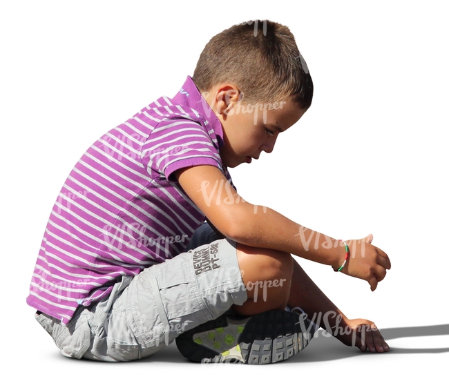 small boy sitting on the ground and playing