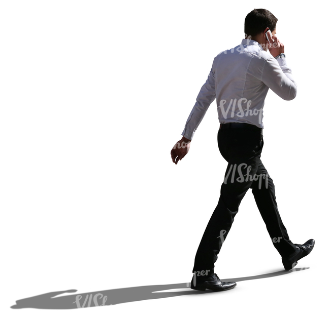 backlit businessman walking and talking on the phone