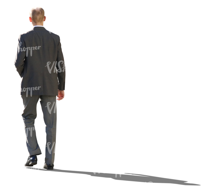 backlit businessman in a grey suit walking